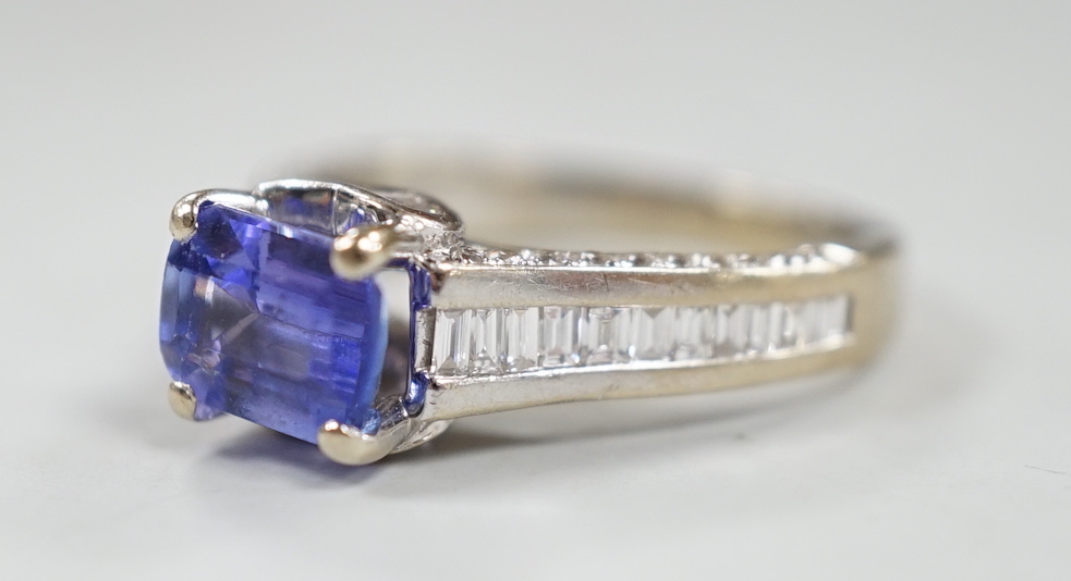 A modern 18ct gold and single stone emerald cut tanzanite set dress ring, with graduated baguette and round cut diamond set shoulders and graduated baguette cut diamond set heart shaped setting, size I, gross weight 4.7